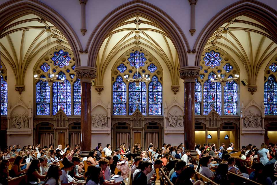 Interior of college church full of students attending mass