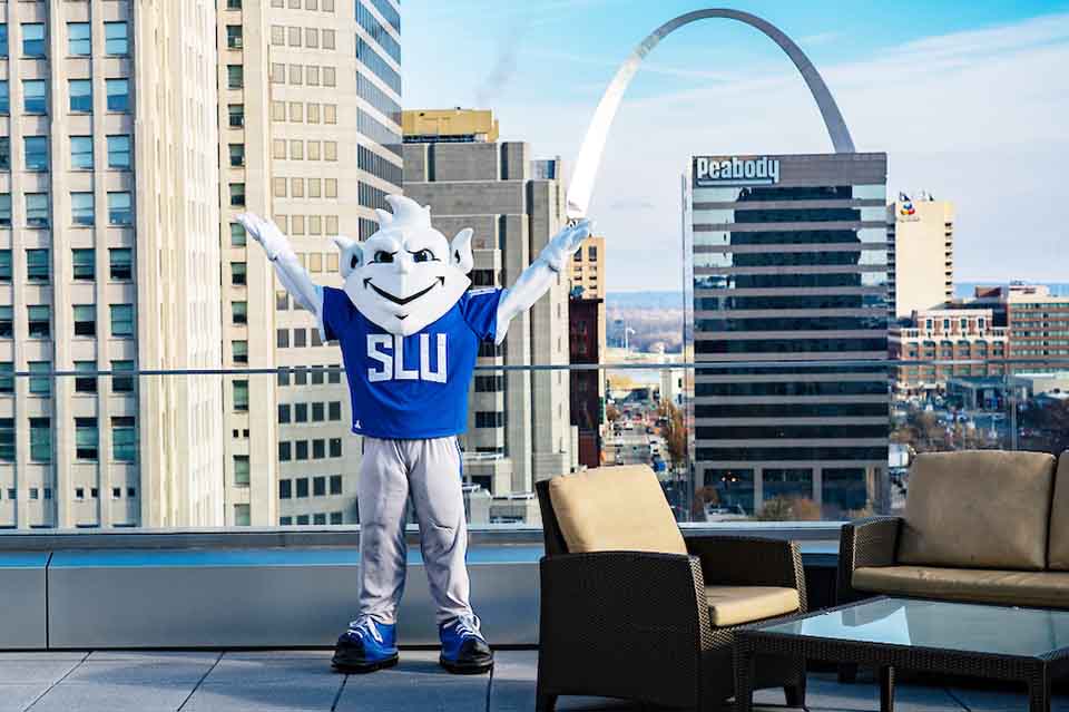 SLU Billiken mascot standing on a rooftop near the Arch