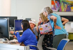 A group of students and advisor gather around a computer screen