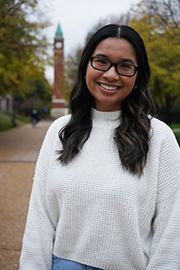 A headshot photo of Emily Tran with a clocktower and trees in the background.