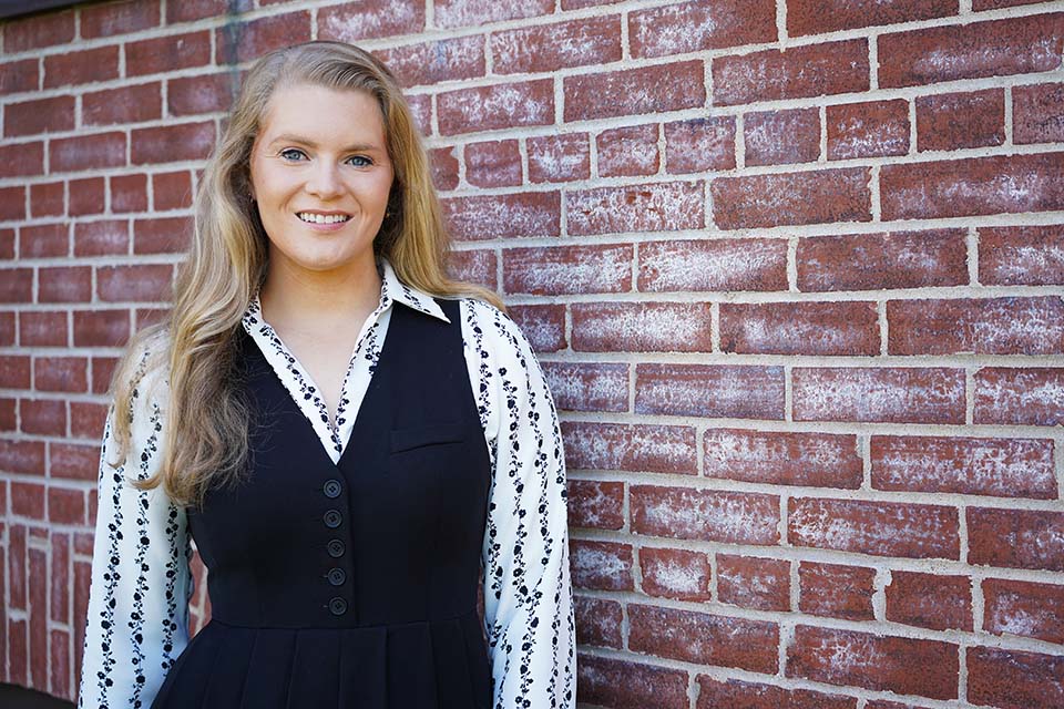 Faith Whatley-Blaine poses for a photo in front of a brick wall.