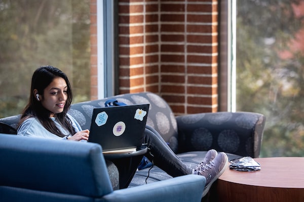 A SLU student works on her laptop while sitting on a couch in Pius XII Memorial Library.