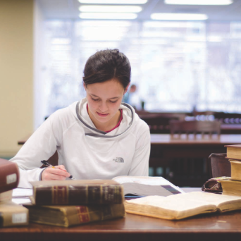 A student studies a manuscript in Pius Library