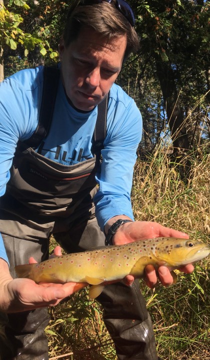 Jason Knouft, Ph.D., holds a fish while researching in an aquatic ecosystem