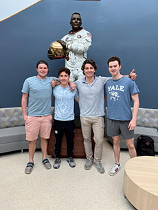 Team members posed in front of an astronaut statue